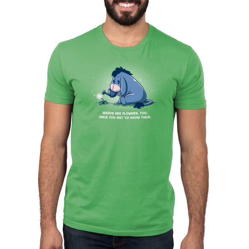 A man wearing an officially licensed Disney Weeds Are Flowers Too green t-shirt with an image of Eeyore the donkey.