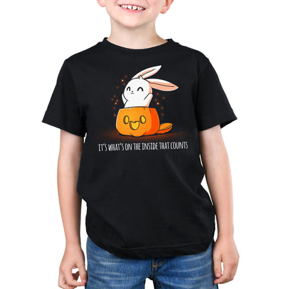 A boy wearing a black TeeTurtle t-shirt with a bunny in a pumpkin, creating a spooky vibe. The t-shirt is called "What's on the Inside (Glow)".
