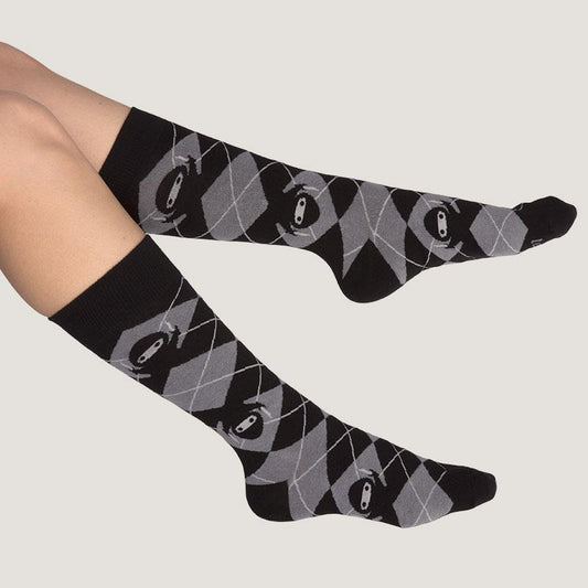 A woman's legs with black and grey argyle TeeTurtle Business Ninja socks.