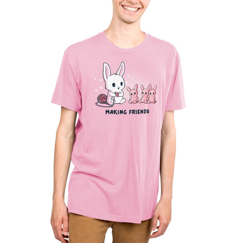 Premium Cotton T-shirt_Teeturtle Making Friends Pink t-shirt Featuring a white-furred bunny knitting bunny friends out of yarn.