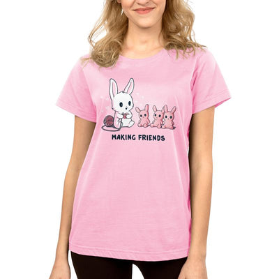 Premium Cotton T-shirt_Teeturtle light pink Making Friends apparel featuring a white bunny knitting 3 bunny friends out pink of yarn, caption reads, "Making Friends'.