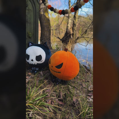 A video of all three Halloween Cloudheads plushies outside by a lake and a gravestone. 