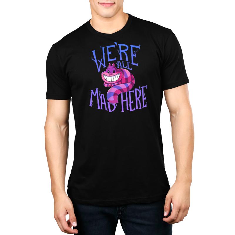 A man wearing an officially licensed Disney t-shirt that says "We're All Mad Here" featuring the Cheshire Cat from Alice in Wonderland.
